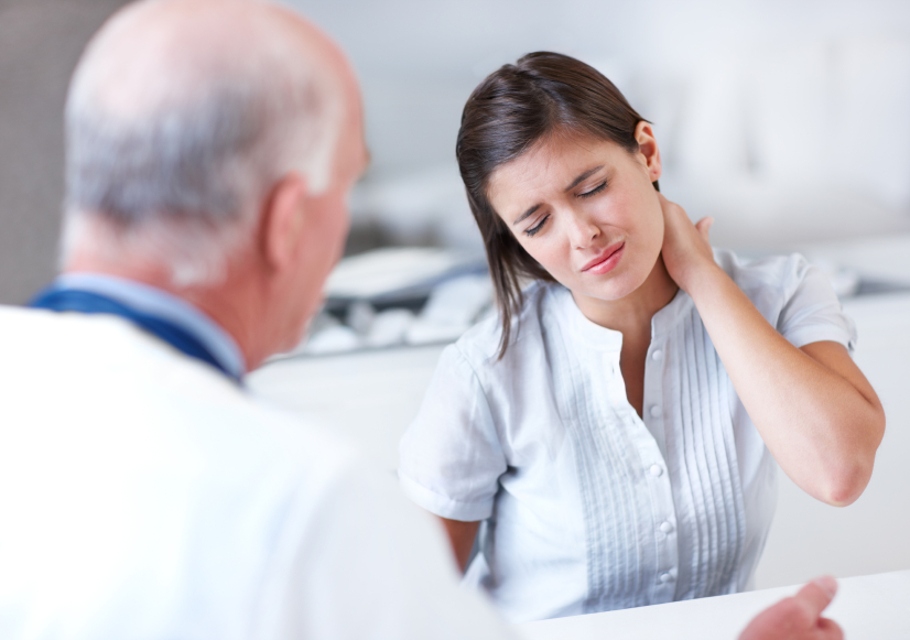 Young woman wincing with pain in a consultation with her doctor - copyspace